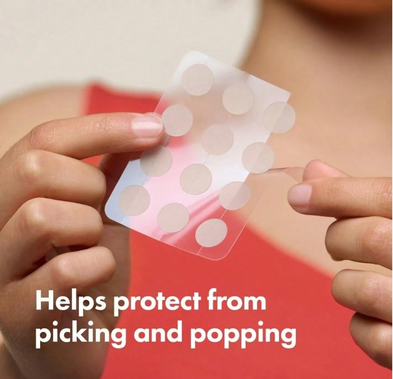Hands holding a sheet of round stickers with text 'Helps protect from picking and popping' on a blurred background.